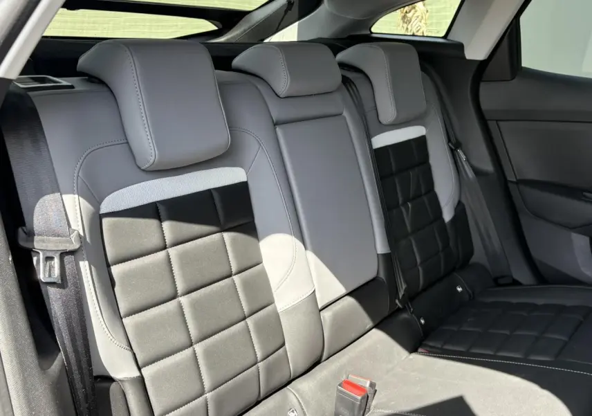 Vue intérieure des sièges arrière gris clair et noir de la Citroën C4 Hybrid 2025, avec ceintures de sécurité visibles.