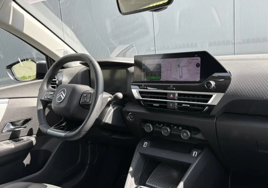 Vue intérieure côté conducteur du tableau de bord noir avec écran tactile GPS et volant Citroën C4 Hybrid 2025.