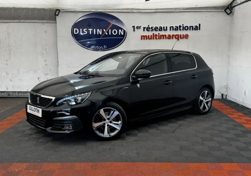 Peugeot 308 noir vue 3/4 avant droit dans un showroom avec jantes alliage et phares LED allumés.