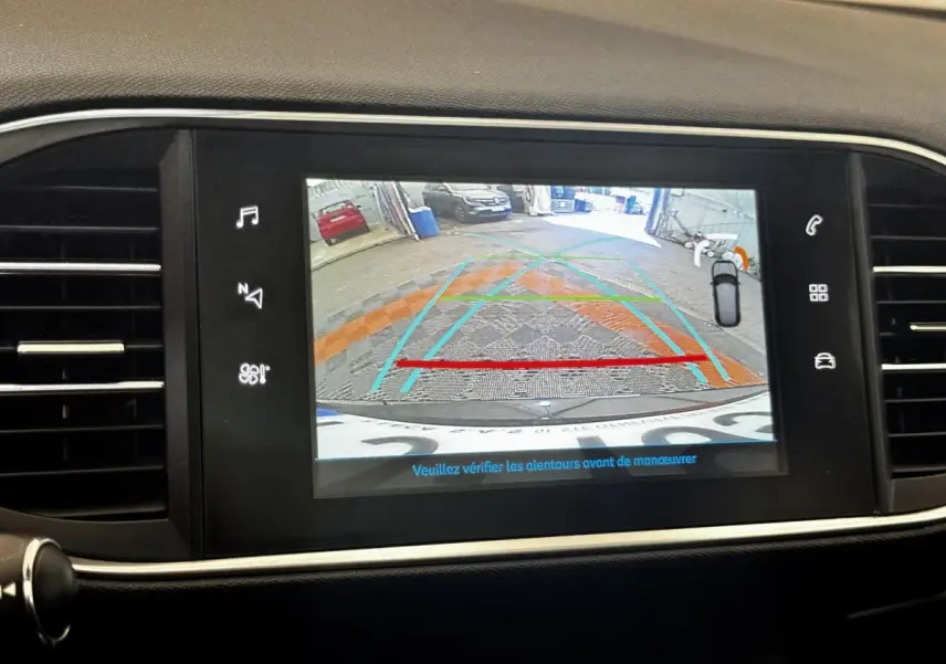 Écran tactile intérieur montrant la caméra de recul avec guidage de trajectoire sur Peugeot 308 noire.