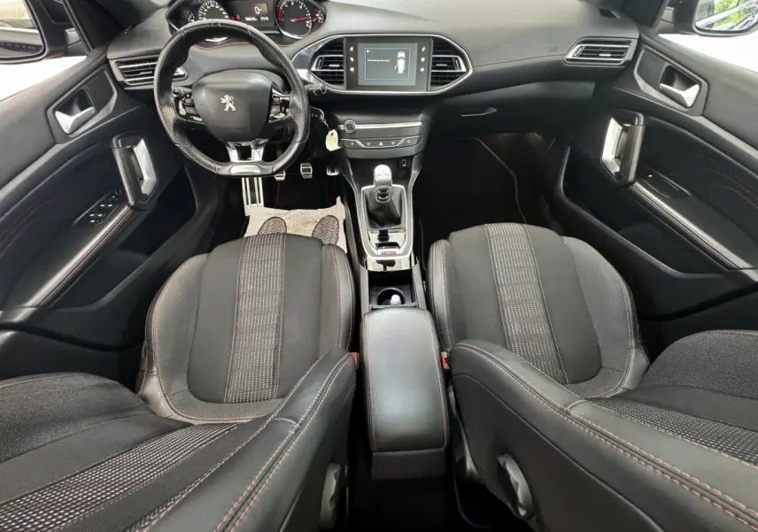 Vue intérieure avant de la Peugeot 308 GT Line 2018, montrant le volant cuir, la console centrale avec boîte manuelle et l’écran tactile.