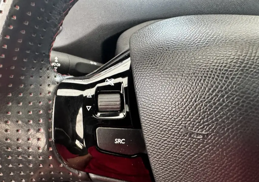 Gros plan sur les commandes gauche du volant cuir perforé de la Peugeot 308 GT Line 2018 noir.