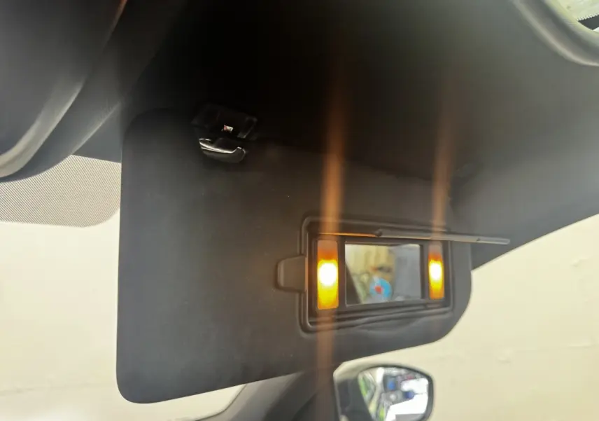Détail intérieur du pare-soleil avec miroir éclairé sur la Peugeot 308 noire, vue côté conducteur.