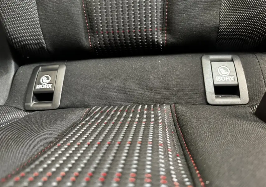 Gros plan sur la banquette arrière noire de la Peugeot 308 avec fixation ISOFIX et surpiqûres rouges.