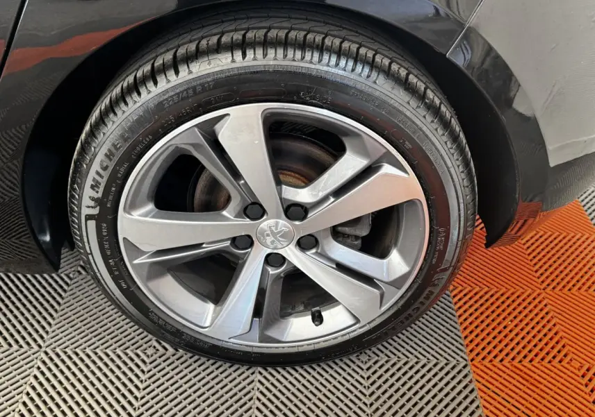 Gros plan sur la roue avant droite noire d’une Peugeot 308 1.5 BlueHDi 130 S&S GT Line avec jante alliage grise.