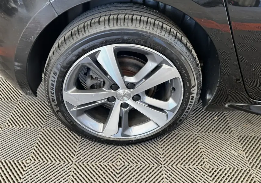 Gros plan sur la roue avant gauche de la Peugeot 308 noire, avec jante alliage et pneu Michelin visible.