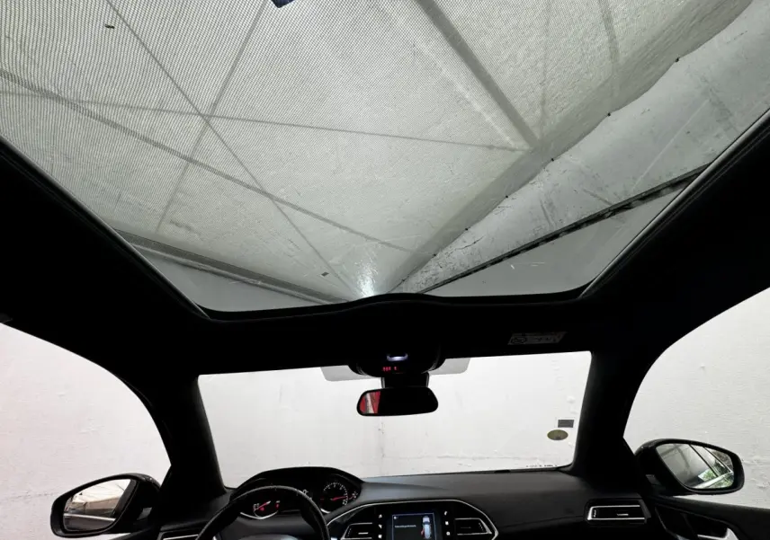 Vue intérieure avant du Peugeot 308 noir 2018, avec toit panoramique et tableau de bord digital lumineux.