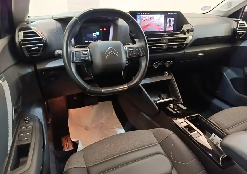 Vue intérieure avant du Citroën C4 X noir 2023, volant cuir multifonctions et écran tactile central affichant la caméra de recul.