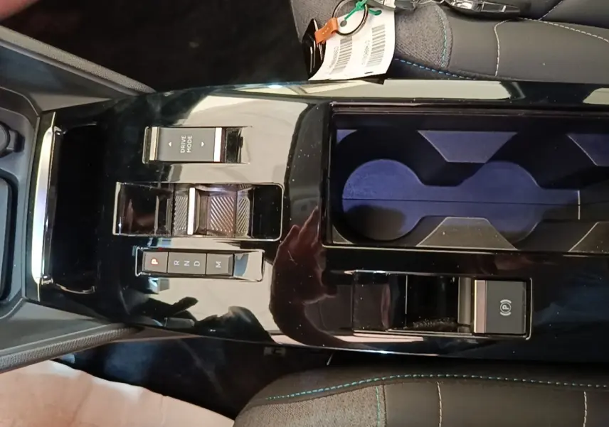 Gros plan sur la console centrale noire brillante du Citroën C4 X avec commandes de boîte auto et porte-gobelets.