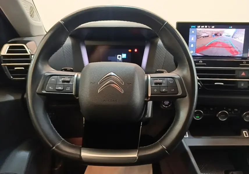 Vue intérieure centrée sur le volant cuir noir de la Citroën C4 X 2023 avec écran tactile de navigation affichant la caméra de recul.