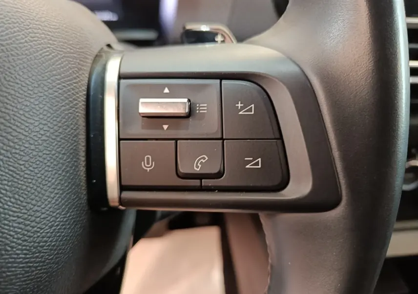 Gros plan sur les commandes gauche du volant cuir noir du Citroën C4 X 2023, boutons multifonctions et micro intégrés.