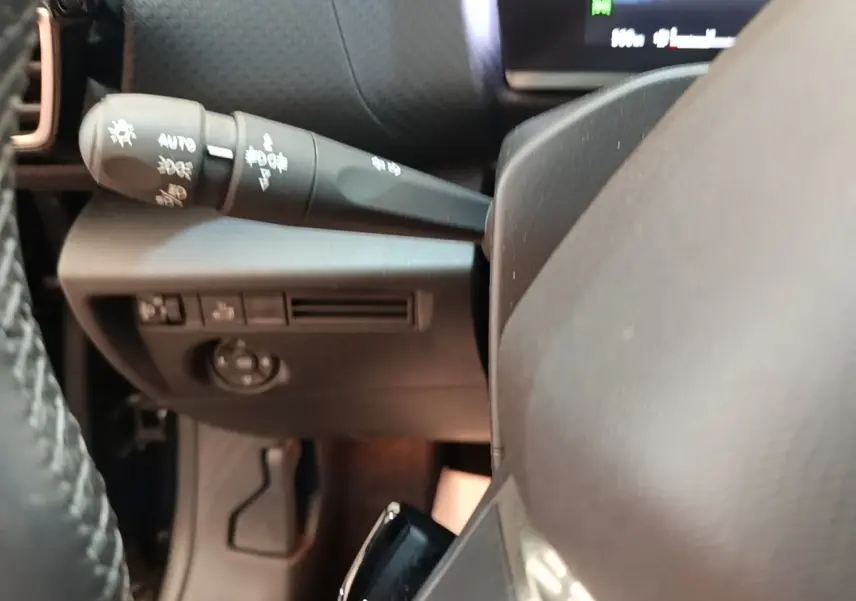 Gros plan sur la commande des phares à gauche du volant cuir noir du Citroën C4 X PureTech 130 Shine 2023.