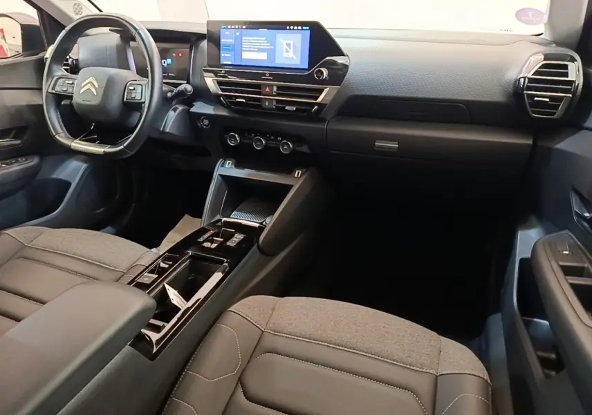 Intérieur avant du Citroën C4 X 2023, vue côté conducteur, tableau de bord noir avec écran tactile central.