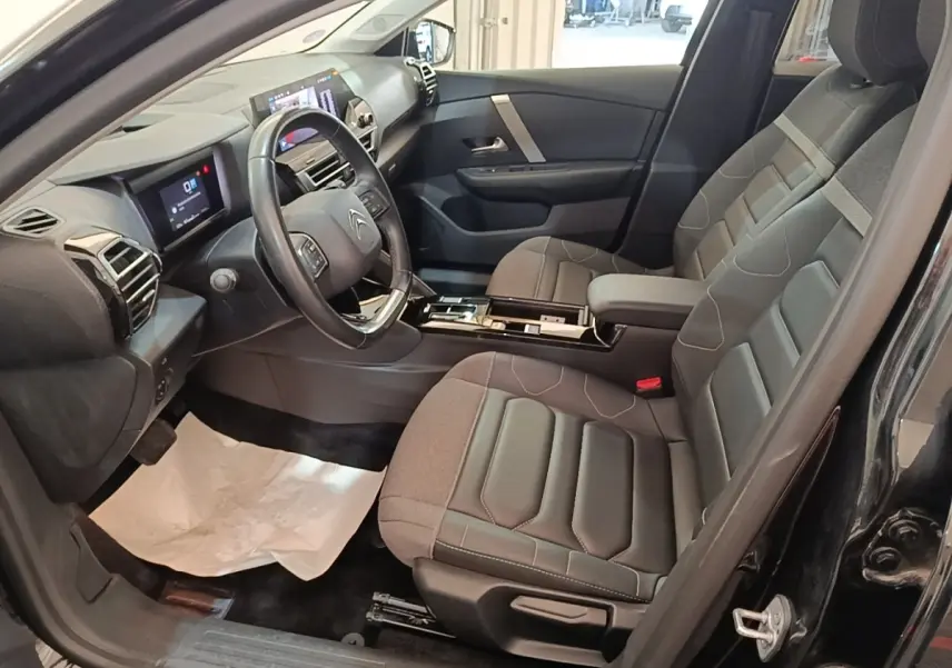 Intérieur avant droit du Citroën C4 X noir 2023 avec sièges tissu et tableau de bord digital tactile.