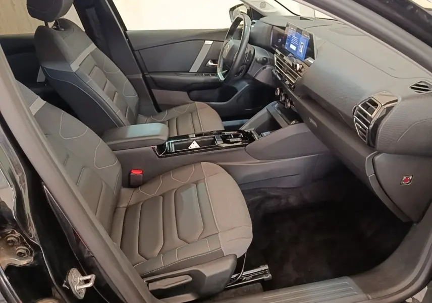 Vue intérieure côté conducteur de la Citroën C4 X noire 2023, avec sièges tissu et tableau de bord moderne.