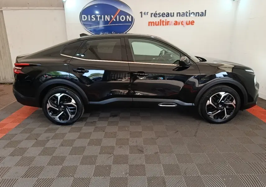 Vue de profil côté gauche d'une Citroën C4 X noire 2023 avec jantes alliage et lignes épurées.