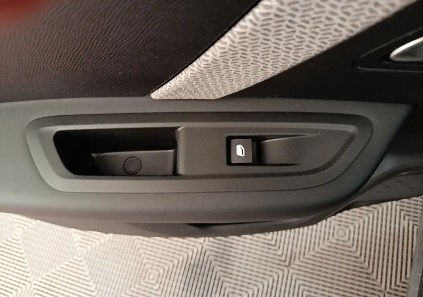 Gros plan sur la poignée intérieure de porte avec bouton de verrouillage, tissu gris et noir visible, intérieur Citroën C4 X.
