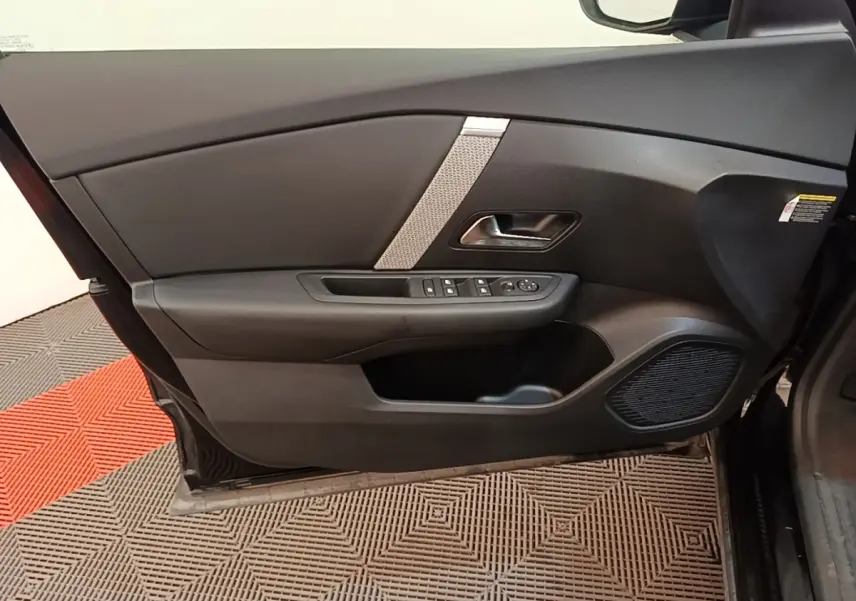 Vue intérieure de la porte avant gauche noire du Citroën C4 X 2023 avec commandes de vitres et haut-parleur intégré.