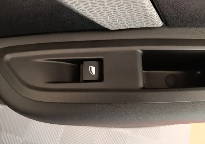Gros plan sur le bouton de commande de la vitre électrique côté intérieur d'une porte de Citroën C4 X noire.