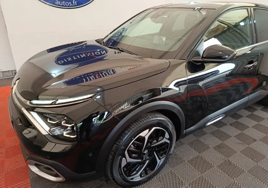 Vue 3/4 avant droit d'une Citroën C4 X noire brillante avec jantes noires et phares LED distinctifs.