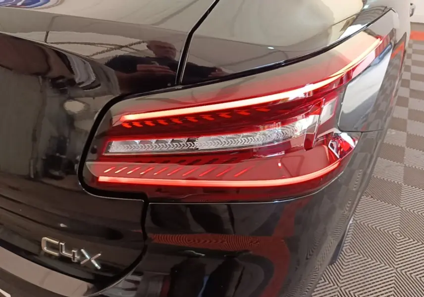 Feu arrière droit allumé et logo C4 X sur la partie arrière noire brillante du Citroën C4 X 2023.