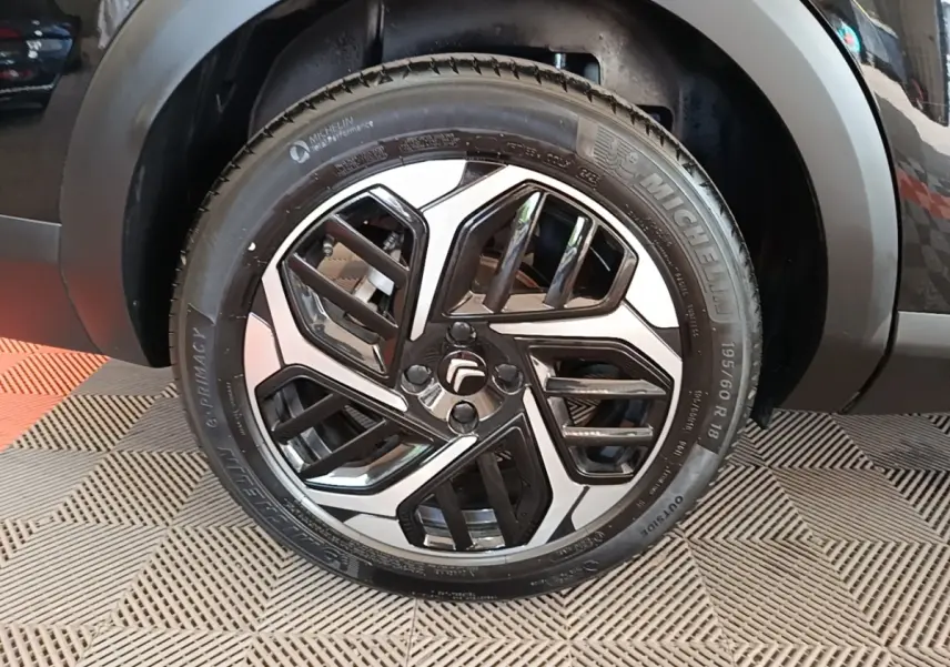 Gros plan sur la roue avant droite noire d'une Citroën C4 X 2023 avec jante alliage bicolore distinctive.