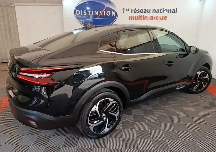 Vue 3/4 arrière droite d'une Citroën C4 X noire 2023 avec feux arrière LED et jantes noires distinctives.