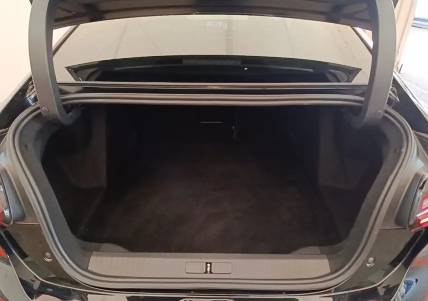 Coffre ouvert vu de l'arrière d'une Citroën C4 X noire 2023, espace de chargement spacieux et propre.