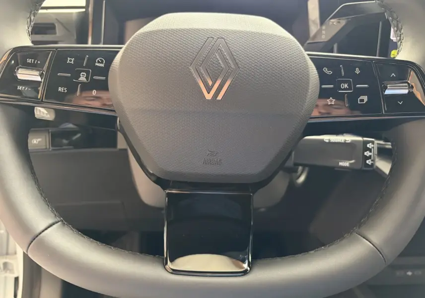 Gros plan sur le volant noir de la Renault Clio 2026 avec commandes intégrées et logo Renault central.