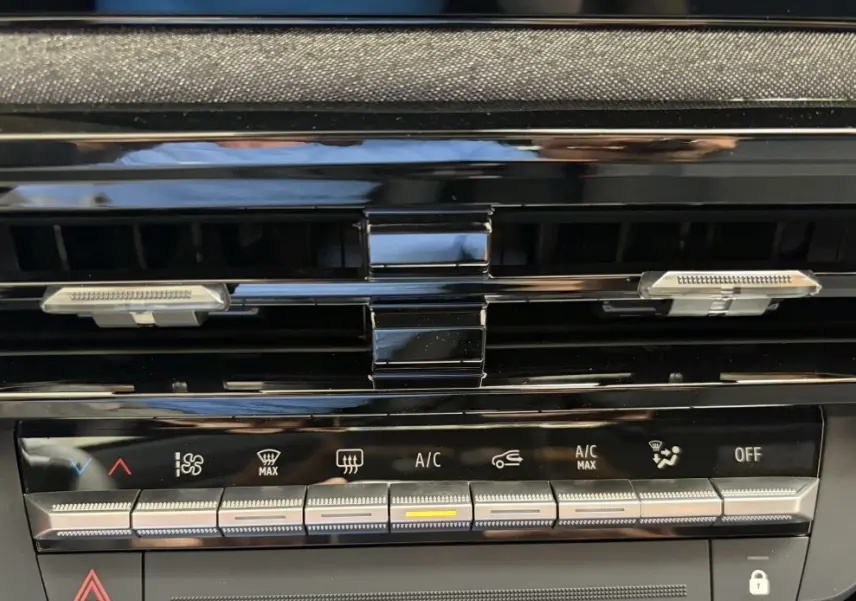 Détail de la console centrale noire de la Renault Clio 2026 blanche, montrant les commandes de climatisation et les aérateurs.