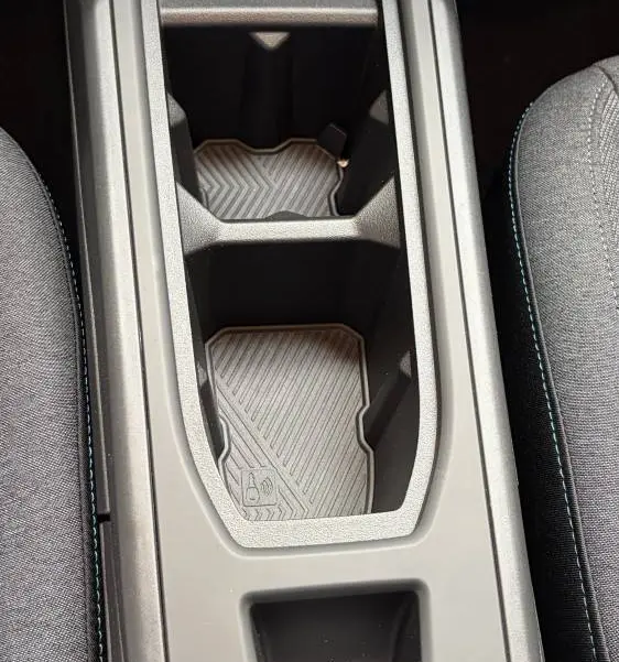 Vue rapprochée de la console centrale noire de la Renault Clio 2026, avec porte-gobelets et commandes électroniques.