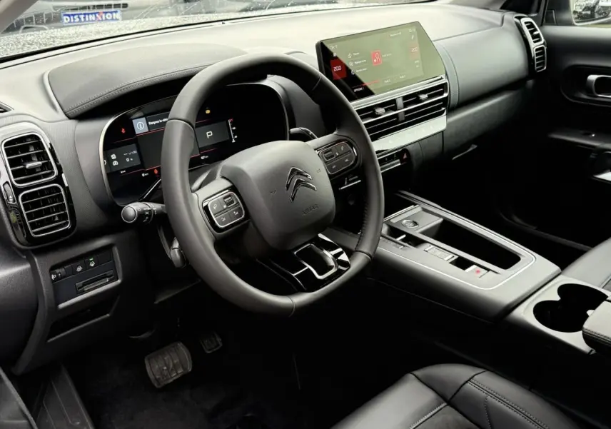 Intérieur noir du Citroën C5 Aircross Hybrid 2025 vu côté conducteur, avec volant cuir et écran tactile 10 pouces.