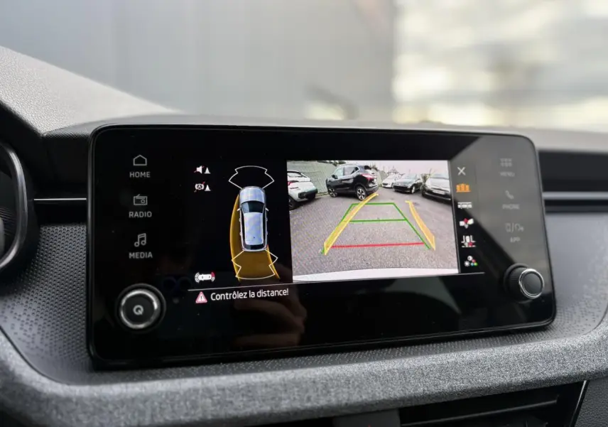 Écran central du Skoda Kamiq gris argent affichant la caméra de recul avec guidage de trajectoire en parking.