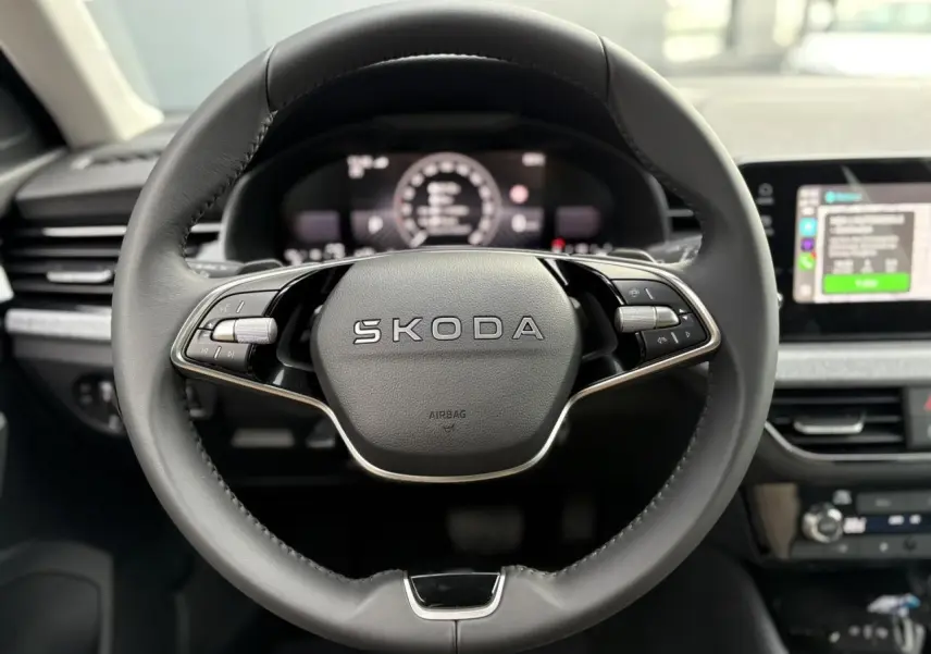 Volant cuir noir avec logo SKODA au centre, tableau de bord numérique et écran tactile du Skoda Kamiq TSI 2025.