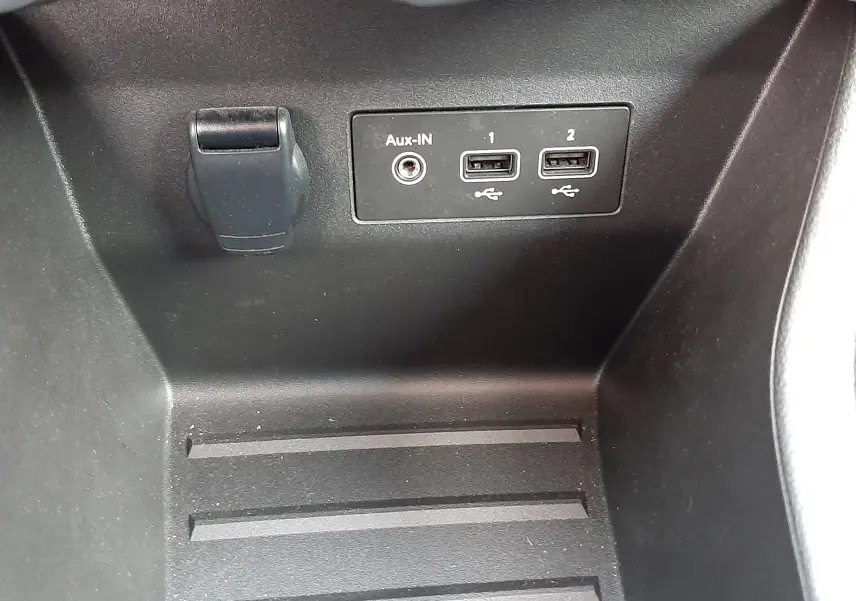 Gros plan sur la console centrale noire de la Renault Clio V avec prises USB et entrée Aux-In visibles.