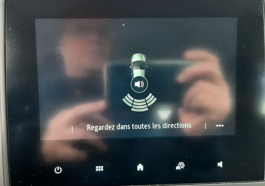 Écran central de la Renault Clio V blanc affichant l'alerte de détection d'obstacles avec icône sonore.