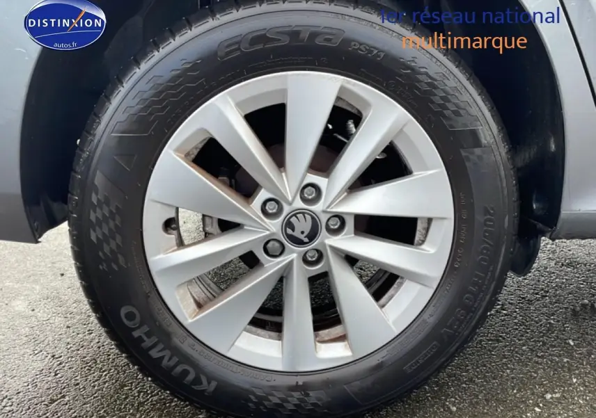 Gros plan sur la jante alu grise avec logo Skoda au centre, montée sur un pneu Kumho d’un Skoda Kamiq gris.