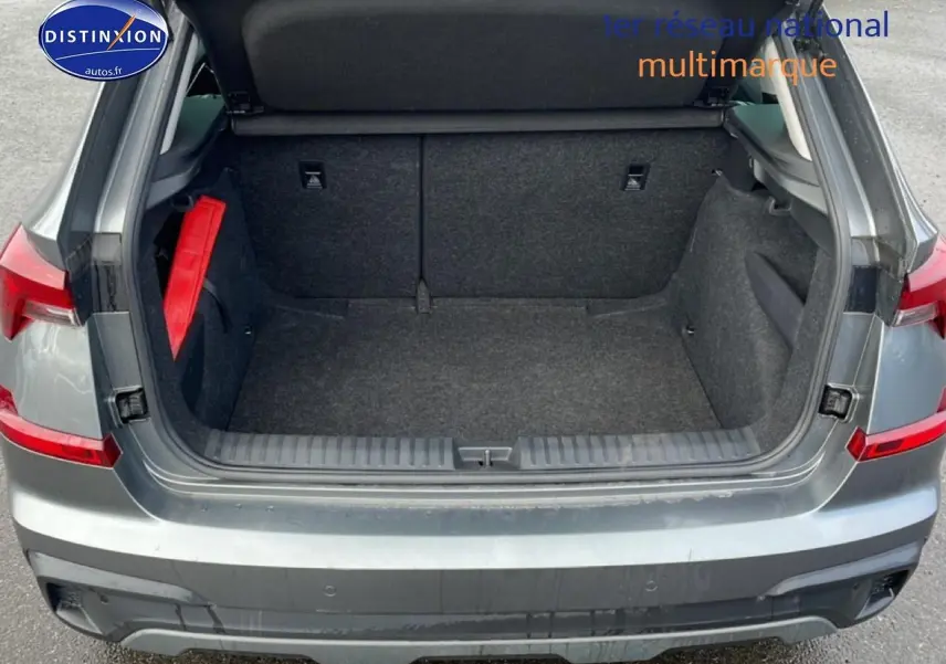 Coffre ouvert vu de l'arrière d'un Skoda Kamiq gris avec intérieur de coffre en tissu noir et triangle de sécurité rouge.