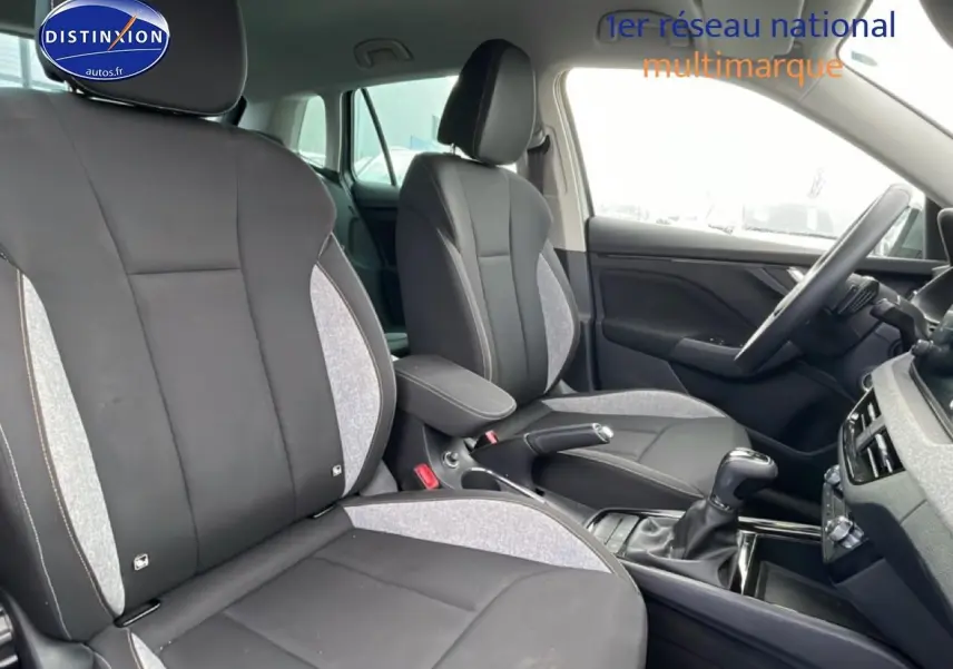 Vue intérieure côté droit du Skoda Kamiq 2025 gris, montrant les sièges avant avec accoudoir central et volant multifonction.