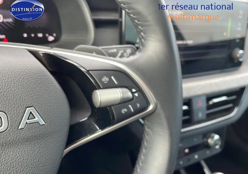 Gros plan sur le volant cuir multifonction gris du Skoda Kamiq 2025 avec commandes intégrées et tableau de bord flou.