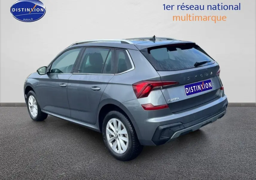 Vue 3/4 arrière droite d’un Skoda Kamiq gris 2025 avec barres de toit et feux arrière LED distinctifs.