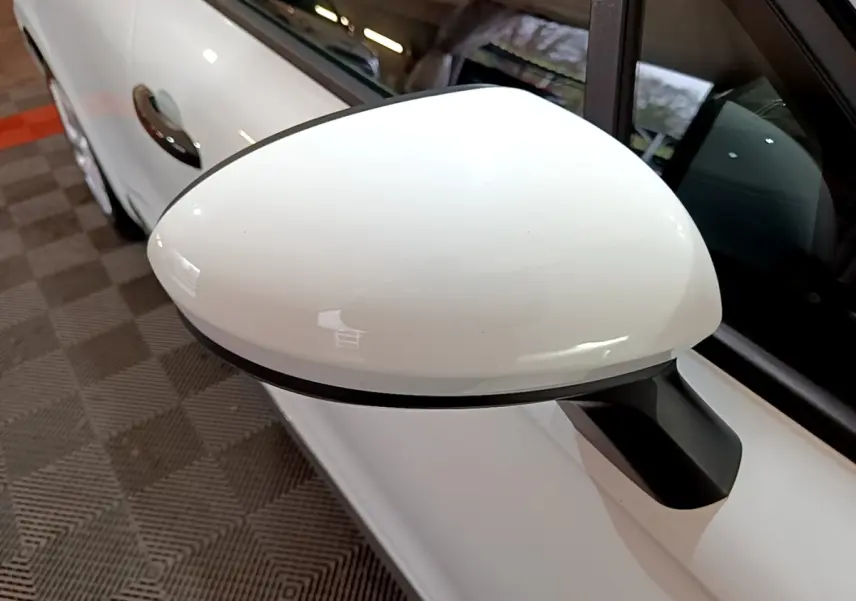 Gros plan sur le rétroviseur droit blanc de la Renault Clio Business 2021, avec porte et vitre partiellement visibles.