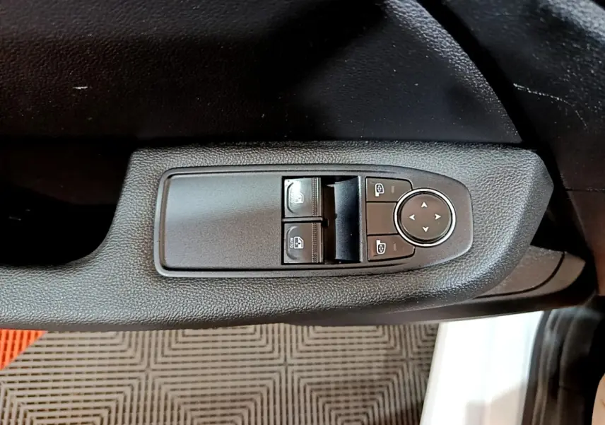 Gros plan sur les commandes de lève-vitres et réglage des rétroviseurs côté conducteur d’une Renault Clio blanche 2021.