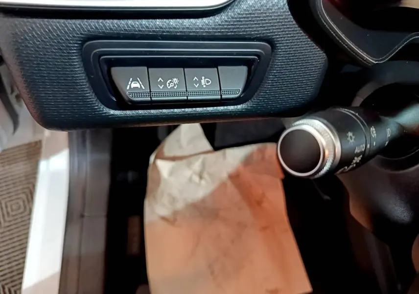 Détail intérieur côté gauche du tableau de bord de la Renault Clio Business blanche, avec commandes d’assistance à la conduite.