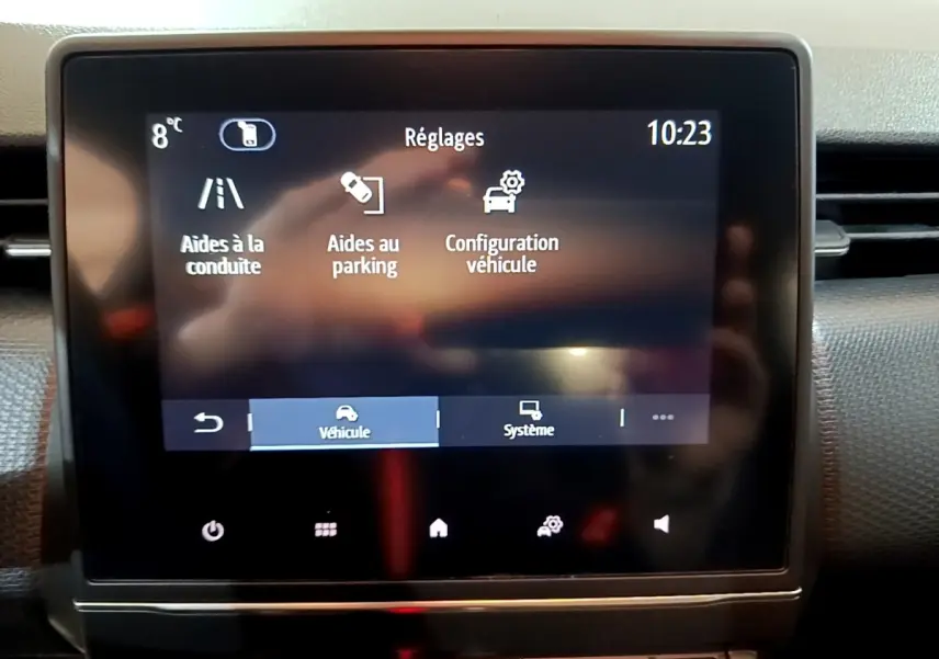 Écran tactile central du tableau de bord de la Renault Clio Business blanc, affichant les réglages d’aides à la conduite et parking.