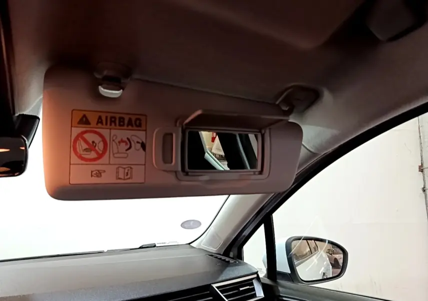 Intérieur de la Renault Clio Business blanche, vue côté passager avec pare-soleil et miroir de courtoisie ouverts.