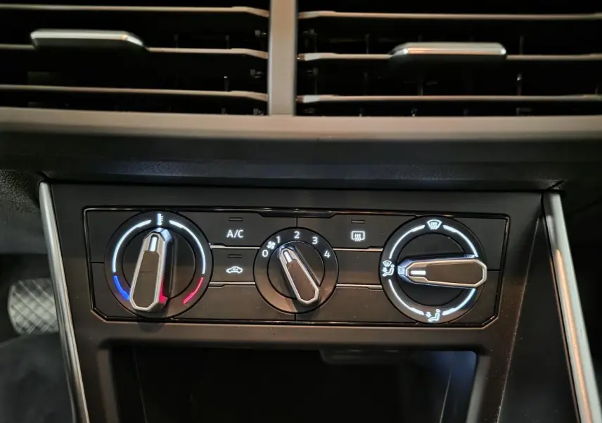 Gros plan sur la commande de climatisation manuelle noire du tableau de bord de la Volkswagen Polo gris 2025.