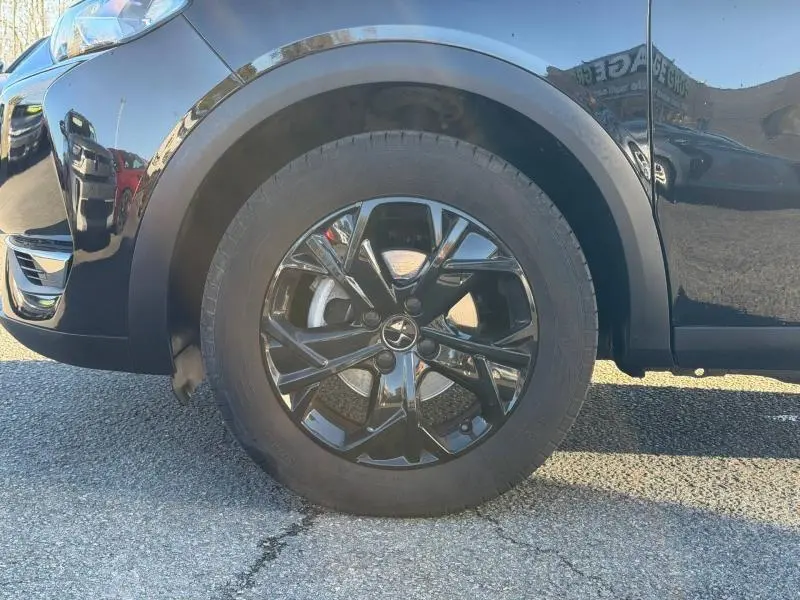 Gros plan sur la roue avant gauche noire brillante du DS3 Crossback 2020, avec jante au design moderne et carrosserie noire.