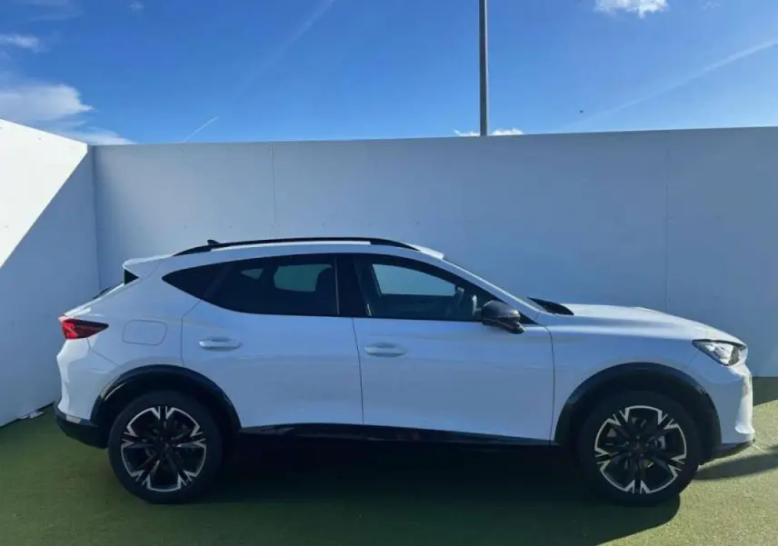 Vue de profil côté gauche d'un CUPRA Formentor blanc 2025 avec jantes noires et toit ouvrant, stationné en extérieur.