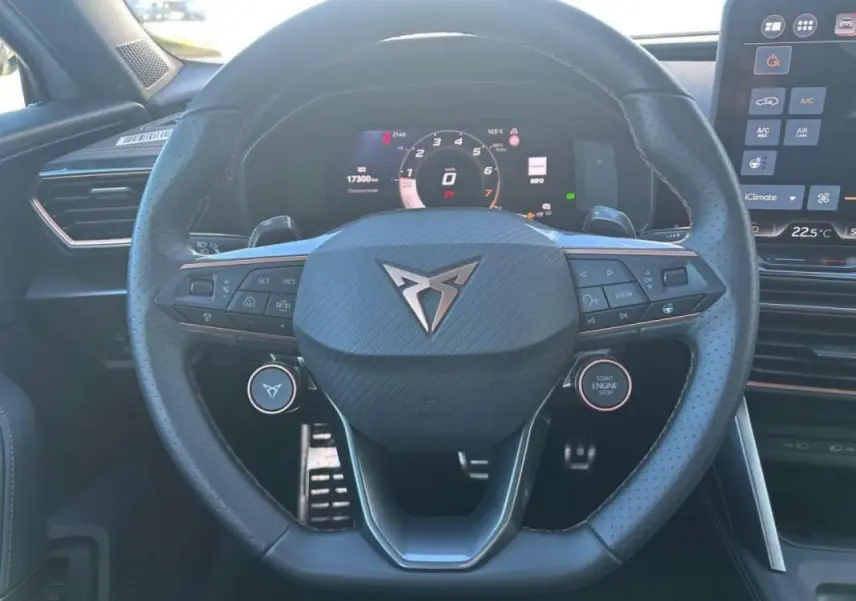 Vue rapprochée du volant noir perforé avec logo CUPRA au centre, tableau de bord numérique et écran tactile à droite.